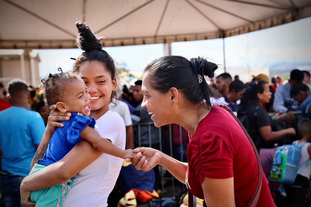 Mujeres venezolanas acurrucan a un bebé mientras esperan para realizar los trámites migratorios. Foto: OIM/Gema Cortes